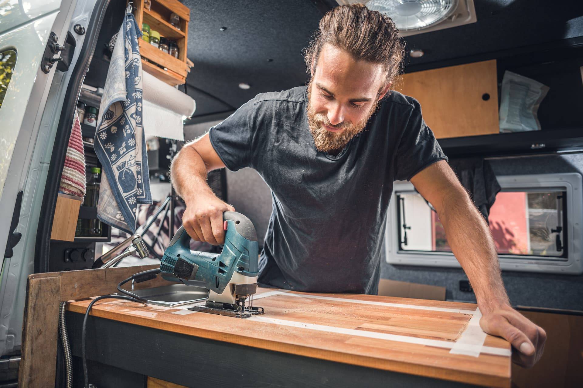 man working on campervan conversion with tools